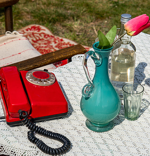 vintage red telephone glass vase with flower and water bottle on table outdoors summer decor