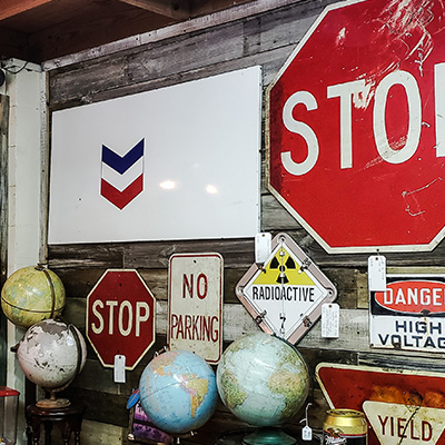 vintage traffic signs and globes displayed on a wooden wall showcasing various warning signals and three distinctive stop signs